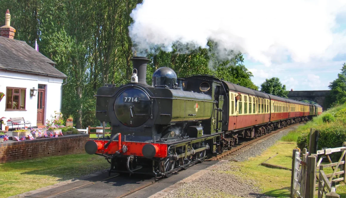 Pannier-7714-passes-Crossing-Cottage-with-blood-and-custard-Mk1s-coaches-in-sun-credit-John-Sherratt-scaled